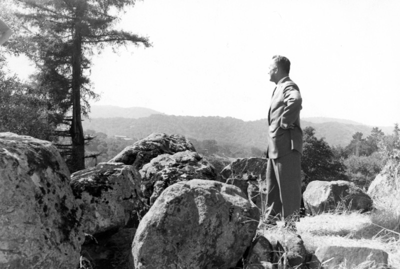 Calvin C. Flint stands atop the large rock outcropping and views the future site of Foothill College in 1958. These rocks still stand on the Foothill campus, marking the entrance to the college. 
