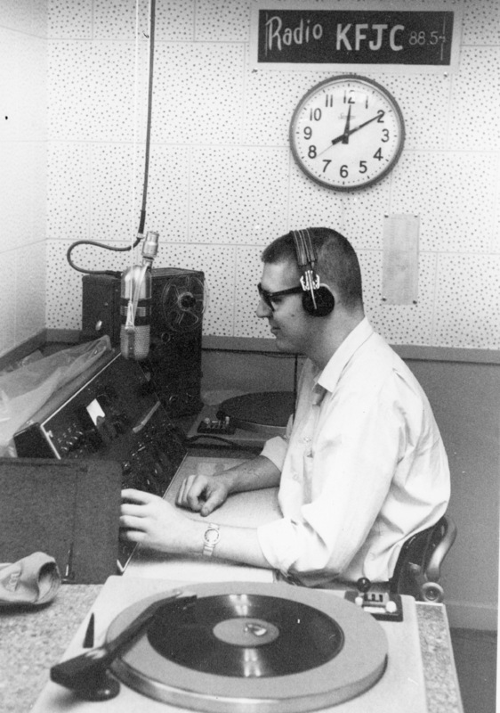 Unidentified student at the broadcast desk of KFJC with record playing in foreground, in the basement of Foothill College in Mountain View. 