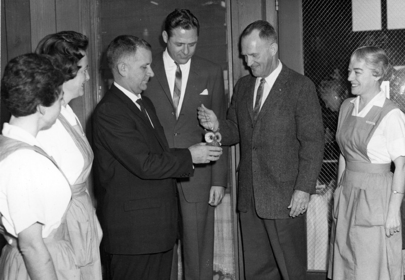 Dr. Calvin C. Flint lights an owl shaped candle to open the Candle Show, sponsored by the Women's Auxiliary of El Camino Hospital in Mountain View. In suits, from left to right: Dr. Clark Snead, hospital administrator Ed Hawkins, Dr, Calvin Flint. Nurses not identified; photo taken in early 1960s.
