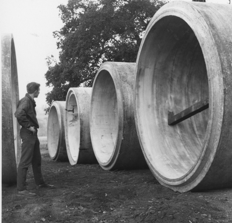 An unidentified man examines the huge concrete sewer lines before they are lowered into place.