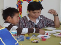 Male college student and young boy working at art table.