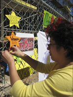 Artist Rodriguez attaches small artwork to chain-link fence surrounding construction site for new Euphrat Museum.