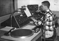 Bob Ballou, station manager, sits at the radio controls and speaks the first official words on KFJC in this photo from the October 23, 1959 edition of the Foothill Sentinel. 