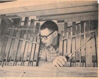 Photograph of Roger Murray examining the inside workings of a barrel organ. Photograph from the June 6, 1961 edition of The (Los Altos) Town Crier.