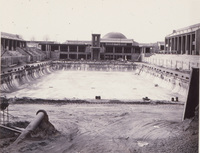 The two swimming pools at De Anza are almost complete. A concrete tower for diving can be seen at the far end of the pool and, just behind the diving tower is the planetarium dome. 