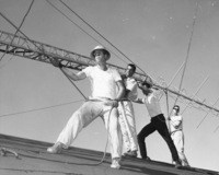 Four men raising the KFJC radio antenna on the roof of the Foothill College building in Mountain View. Pictured from left to right are Bob Ballou, Jim Fernbaugh, Nathan Ballard and Roger Murray. Photographer Gary Pagano for the Foothill Sentinel, October 9, 1959.