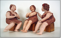 Sculpture of three women casually sitting on boxes, bare feet, talking animatedly.