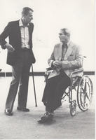 Dr. Diesner, in wheelchair, in conversation with artist with cane.