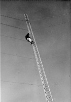 unidentified man works on upper half of upright radio tower