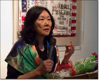 Connie Young Yu speaking in front of a Flo Oy Wong artwork.