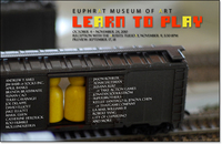 Toy train boxcar with game pieces inside. Basic show info.