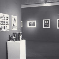 Installation photo with art on dark painted walls.