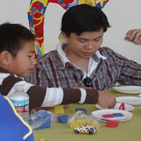 Male college student and young boy working at art table.