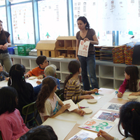 Artist talks with a group of students at their tables, ready to create art.