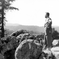Calvin C. Flint stands atop the large rock outcropping and views the future site of Foothill College in 1958. These rocks still stand on the Foothill campus, marking the entrance to the college. 