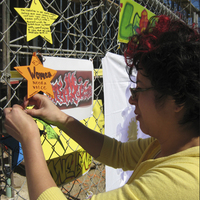 Artist Rodriguez attaches small artwork to chain-link fence surrounding construction site for new Euphrat Museum.