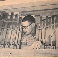 Photograph of Roger Murray examining the inside workings of a barrel organ. Photograph from the June 6, 1961 edition of The (Los Altos) Town Crier.