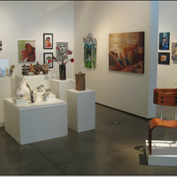 Multiple small sculptures on pedestals, multiple paintings on walls.