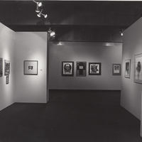 Exhibition installation photo from afar with multiple artworks on the walls.