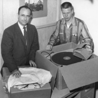 Bob Ballou, the first station manager of KFJC, opens boxes of new equipment, including the turntable and wall clock with George Castleberry. Photo from April 3, 1959 edition of Foothill Sentinel.