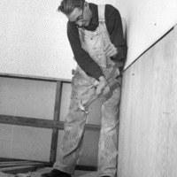 Unidentified man hammering wall during construction of KFJC radio studio in basement of Foothill College, 1959. 