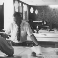 Calvin Flint, Foothill College's first President, later the first District Superintendent, reviews blue prints for the award winning design of Foothill College. Earnest J. Kump, chief architect, sits with his back to the camera.