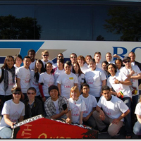 Around 30 students posing in front of a bus.