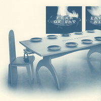 Modernist dining table and chair. Place set with plates, no utensils. 'Fear of fat' on back wall.