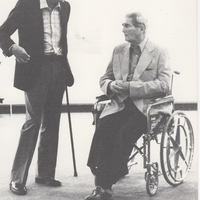 Dr. Diesner, in wheelchair, in conversation with artist with cane.