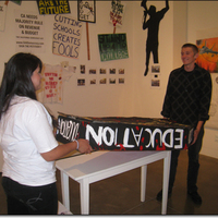 Two activist students installing a coffin-like sculpture with 'Education' written on it.