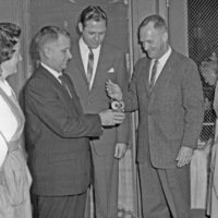 Dr. Calvin C. Flint, holding the match, lights an owl shaped candle to open the Candle Show fundraiser sponsored by the Women's Auxiliary of El Camino Hospital in Mountain View.  Dr. Clark Snead (holding candle)  and Ed Hawkins of El Camino Hospital stand next to him. The nurses are not identified. Picture taken at El Camino Hospital in early 1960s. 