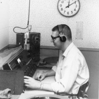 Unidentified student at the broadcast desk of KFJC with record playing in foreground, in the basement of Foothill College in Mountain View. 