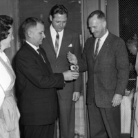 Dr. Calvin C. Flint lights an owl shaped candle to open the Candle Show, sponsored by the Women's Auxiliary of El Camino Hospital in Mountain View. In suits, from left to right: Dr. Clark Snead, hospital administrator Ed Hawkins, Dr, Calvin Flint. Nurses not identified; photo taken in early 1960s.
