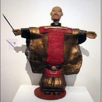 Warrior sculpture with hands outstretched to sides, holding a baton.