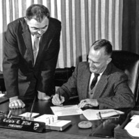Earl Goddard, Chairman of the board of the Perham Foundation, looks on as Dr. Calvin C. Flint, president of Foothill College, signs an agreement paving the way for a fund drive by the Foundation to finance an electronics museum on the Foothill College Campus. Photo taken in 1960s; precise date unknown. 