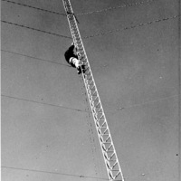 unidentified man works on upper half of upright radio tower