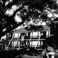A student leans on a car in front of the Highway School on El Camino Real in Mountain View, California. This school was the temporary location of Foothill College from 1958-1961. The permanent campus on El Monte Road in Los Altos Hills opened to students in September of 1961.