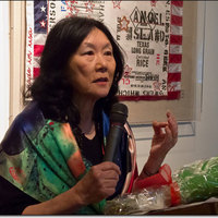 Connie Young Yu speaking in front of a Flo Oy Wong artwork.