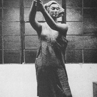 Photo of sculpture of woman holding torch. Background is empty warehouse.